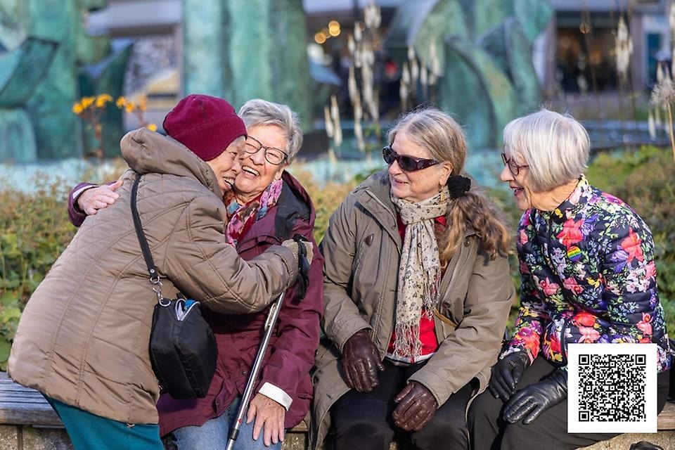 Glada vänner på en parkbänk hälsar på en vän