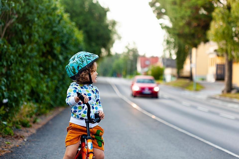 En pojke som cyklar bredvid en bilväg