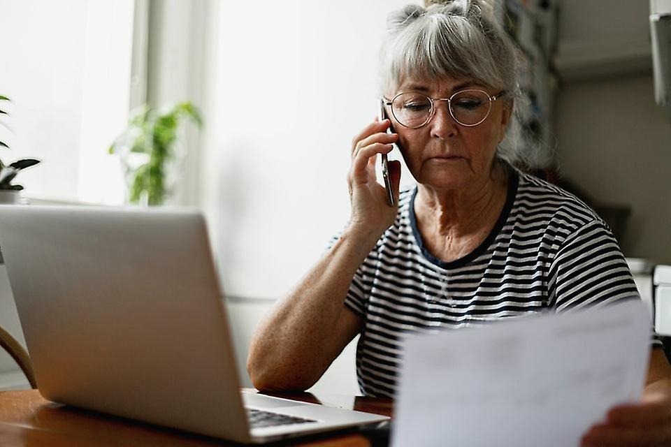 Kvinna som pratar i telefonen och tittar på ett dokument