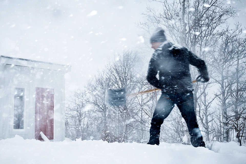 Man skottar snö i storm.