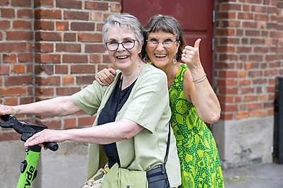 Två kvinnor åker elsparkcykel.