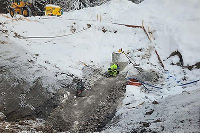 Person i varselkläder arbetar med att koppla in en brunn bakom brandstationen.